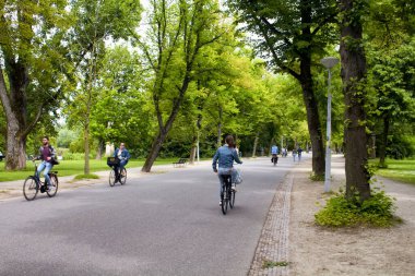Amsterdam 'daki Vondelpark' ta bisiklet süren, yürüyen, ağaç ve yol gezen insanların görüntüsü. 47 hektarlık bir halk parkı. Bu bir yaz günü..