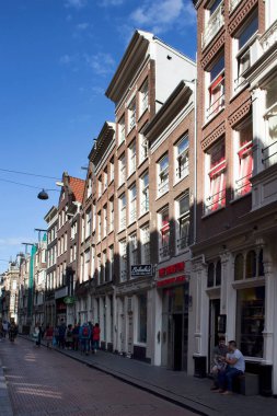 Amsterdam 'da Warmoesstraat caddesinde yürüyen insanların görüntüsü. Birçok kafe, restoran ve mağazası olan en eski sokaklardan biridir. Güneşli bir yaz günü..