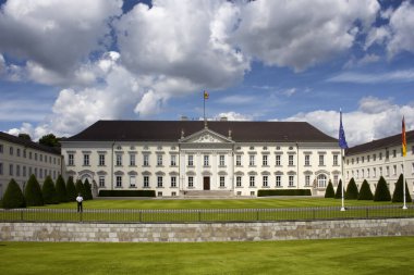 Berlin 'de Bellevue Sarayı' nın dramatik bulutların altında manzarası. Sahnede bir de gardiyan var.