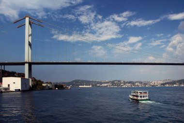 Tanımlanamayan insanlarla dolu bir tur teknesinin görüntüsü, Boğaz Köprüsü. Açık bulutlu güneşli bir yaz günü..