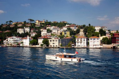 Boğaz 'da küçük ahşap bir balıkçı teknesi. Arka planda, İstanbul 'un Asya yakasındaki tarihi, eski Türk / Osmanlı evleri yer alıyor. Güneşli bir yaz günü..
