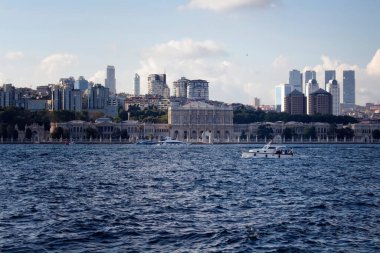 İstanbul Boğazı 'ndaki tarihi binanın önünden geçen iki beyaz yatın görüntüsü. Avrupa tarafında da gökdelenler var.