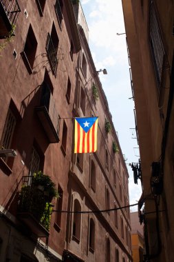 Barcelona 'nın Ciutat Vella ilçesindeki (Gotik Mahallesi) dar sokak ve tarihi binalarda katalan bayrağı görülüyor. Güneşli bir yaz günü..
