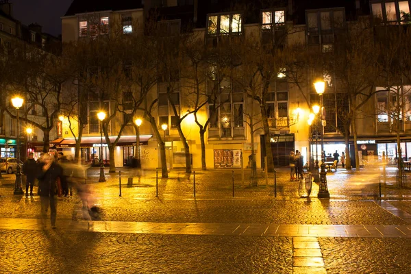 View of street lights and city square at night near Center Pompidou in Paris. People are in blurry motion.