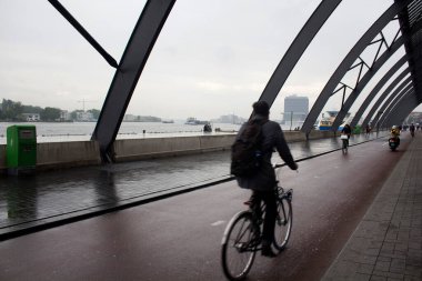 Amsterdam Centraal adlı ana tren istasyonunun arkasında bisiklet süren bir adamın bulanık görüntüsü. Yağmurlu bir yaz günü..