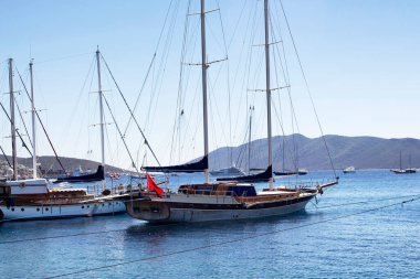 Bodrum kalesinin önündeki turkuaz suya park edilmiş lüks yatlar (yelkenli tekneler). Görüntü Ege ve Akdeniz kıyı yaşam tarzının kültürünü gösteriyor.