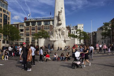 Amsterdam 'daki Ulusal Anıt' ın önünde takılan insanların görüntüsü. Mavi gökyüzü güneşli bir yaz günü..