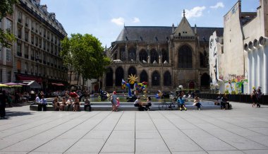İnsanlar Stravinsky çeşmesinin etrafında oturur ve Paris 'in güneşli gününün tadını çıkarırlar. Havuzda birçok çağdaş sanat eseri var.