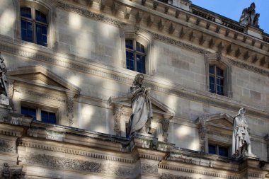 Paris 'te güneşli bir günde Louvre Müzesi' nin alt manzarası. Manzarada heykeller ve güçlü gölgeler var.