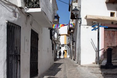 Gündüz vakti İbiza 'nın eşcinsel caddesinde iki genç zenci turist yürüyor. Dar sokak ve beyaz, geleneksel binalar adanın yaşam tarzını ve kültürünü yansıtıyor. Calle de la Virgen caddesi..