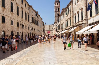 Birçok turist, güneşli yaz gününde Dubrovnik 'in eski büyük caddelerinden birinde (Stradun) yürüyor..