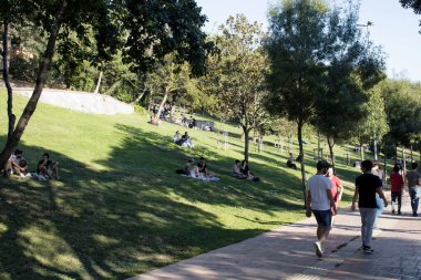 Güneşli bir yaz gününde Nisantasi / İstanbul 'daki parkta çimlerin üzerinde yürüyen insanların görüntüsü.