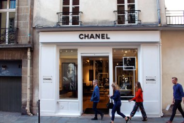 İnsanlar Le Marais Paris 'te ünlü, uluslararası bir Fransız lüks markası mağazasının önünden geçiyor. Üçüncü arrondissement