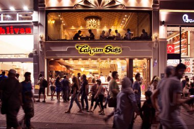 İstanbul 'da gece vakti ünlü bir tatlı dükkanının önünde Istiklal Caddesi' nde yürüyen insanların bulanık görüntüsü..