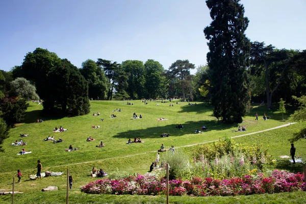 İnsanlar güneşli havanın ve Parc des Buttes-Chaumont parkının tadını çıkarırlar. Güneşli bir bahar günü..
