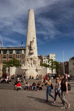 Amsterdam 'daki Ulusal Anıt' ın önünde takılan insanların görüntüsü. Mavi gökyüzü güneşli bir yaz günü..