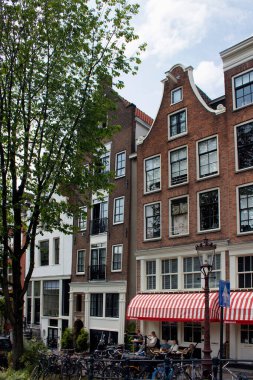 Bir kafede takılan insanları görmek, park etmiş bisikletleri, ağaçları, tarihi, geleneksel ve tipik Amsterdam binalarını görmek. Güneşli bir yaz günü..