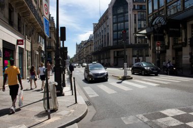 Paris 'in en önemli ve en işlek caddesinin manzarası. Arabalar ışıklarda bekler. İnsanlar yanlamasına yürür. Dükkanlar manzaralı.