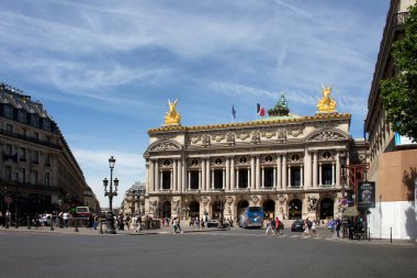 Paris 'teki ünlü opera binası. İnsanlar karşıdan karşıya geçiyor ve araçlar görüş alanımızda.
