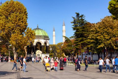 Istasnbul 'daki Sultanahmet bölgesinde yerli halk ve turistler temiz bir Mavi Cami geziyor. İstanbul 'da arka planda Alman Çeşmesi ve Mavi Cami minareleri bulunuyor.