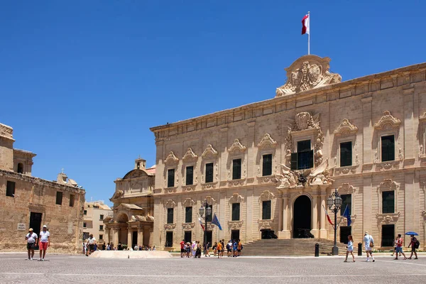 Valletta, Malta 'da Auberge de Castille' in önünde yürüyen insanların görüntüsü.