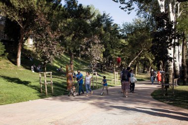 Güneşli bir yaz gününde Nisantasi / İstanbul 'daki parkta çimlerin üzerinde yürüyen insanların görüntüsü.