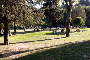 Güneşli yaz gününde Nisantasi / İstanbul 'daki parkta çimlerin üzerinde takılan insanların görüntüsü.