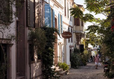 Adam tarihi, eski Cunda (Alibey) adasındaki eski bir sokakta yürüyor. Taş evler Ege mimari tarzını yansıtır. Güneşli bir yaz günü..