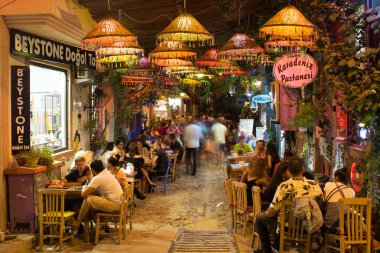 Eski Cunda (Alibey) adasının dışındaki kafelerde sosyalleşen insanların uzun süredir görüntüsü bulanık. Görüntü bölgenin yaşam tarzını ve kültürünü gösteriyor.