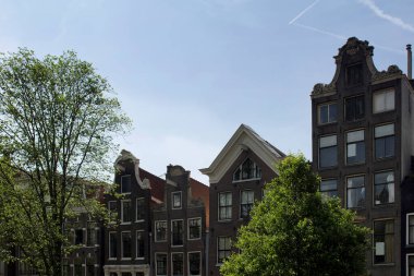Amsterdam 'da mavi gökyüzü arka planına sahip Hollanda mimari tarzını gösteren tarihi, geleneksel ve tipik binaların manzarası. Güneşli bir yaz günü..