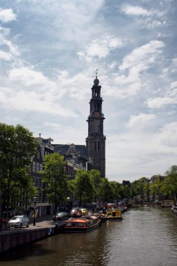 Kanal turu tekneleri, Westerkerk kilisesinin kulesi, ağaçlar ve tarihi binalar. Güneşli bir yaz günü..