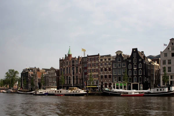 アムステルダムのオランダの建築様式を反映したアムステルダム川 運河のボートや歴史的 伝統的かつ典型的な建物の眺め 曇天の夏の日 — ストック写真