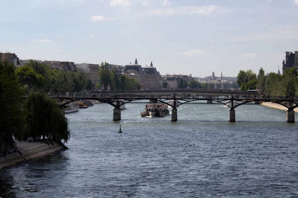 セーヌ川のツアーボートは パリのポン アート橋を渡ろうとしています 恋人たちの南京錠はこのアーチ型の橋の手すりを詰め込み セーヌ川沿いのパノラマビューを提供します — ストック写真