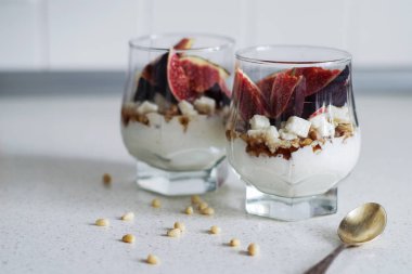 Taze incir ile vanilya krem, peynir, fındık ve akçaağaç şurubu bir cam ölçek şanti. Sağlıklı gıda, diyet ve kahvaltı konsepti. Taze yoğurt tohum ve meyve ile yapılmış