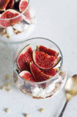 Taze incir ile vanilya krem, peynir, fındık ve akçaağaç şurubu bir cam ölçek şanti. Sağlıklı gıda, diyet ve kahvaltı konsepti. Taze yoğurt tohum ve meyve ile yapılmış