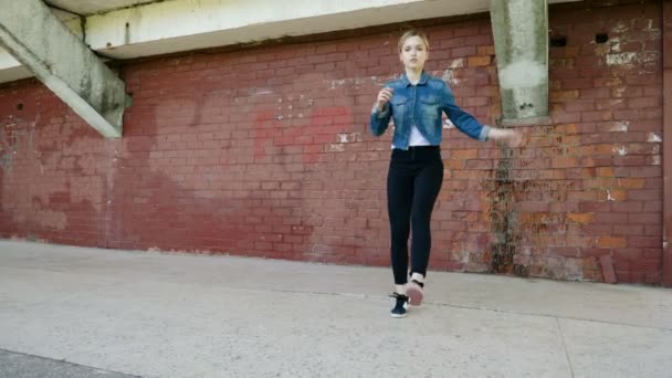 Pouliční tanečnice. Mladá talentovaná žena se roztančí a provádí volný styl do tanec před červenou cihlovou stěnou. 4k
