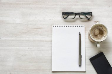 Ahşap ofis masaüstü ile kahve fincanı, Gözlük, telefon, kalem ve Kağıt kopya alanı ile. Üstten görünüm. 