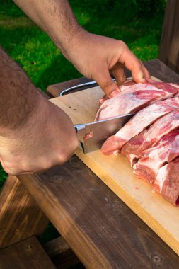 Ahşap arka plan üzerinde havai görünümü domuz ham parçasının. Bir parça taze kemiksiz domuz, boyun bölümü veya yaka. Büyük parça ahşap arka plan üzerinde kırmızı çiğ et. Kasap eller yakın çekim: güneşli günde ahşap tahta kesme karşılamak