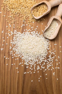 ahşap zemin üzerine susam. İki tür tahta kaşık susam tohumu. Sağlıklı çeşni