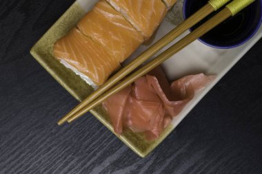 Philadelphia rulo suşi somon, karides, krem peynir, soya sosu, zencefil ile. Ahşap çubuklar ile Japon yemekleri