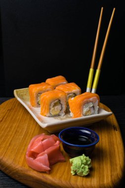 Philadelphia rulo suşi somon, karides, krem peynir, soya sosu, zencefil, wasabi ile. Ahşap çubuklar ile Japon yemekleri