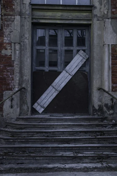 old wooden door all boarded up and old ladder in dark fear evening. Closed door with wooden board background. Hounted house