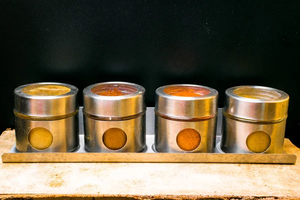 Renkli otlar ve baharatlar metal ve cam kavanoz. Doğal renkler ve üstten görünüm. Sağlık Hindistan baharat. Baharatlı aralığı. Bir dizi farklı baharatlar ve otlar dört şeffaf cam kavanoz.