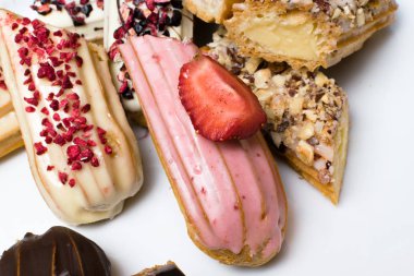 Tatlı lezzetli renkli Fransız eklerleri. Fransız tatlı grubudur. Pasta arka plan. Fransız pasta eklerleri ahududu, krema ve çikolata ile dekore edilmiş, sırlı. Çeşitli seçimi