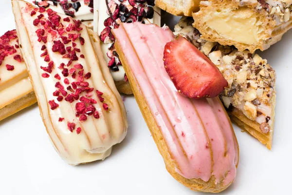 Tatlı lezzetli renkli Fransız eklerleri. Fransız tatlı grubudur. Pasta arka plan. Fransız pasta eklerleri ahududu, krema ve çikolata ile dekore edilmiş, sırlı. Çeşitli seçimi