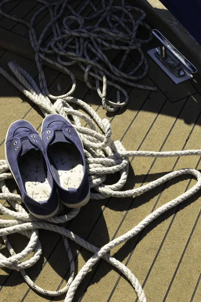 Close-up of a mooring rope with a knotted end tied around a cleat on a wooden pier Nautical mooring rope. Close Boat Rope Tied on Figure Eight Cleat Hitch and shoes with anchors