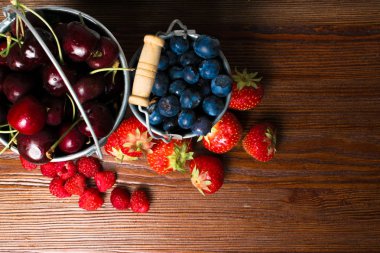 Ahşap arka plan üzerinde meyveleri. Yaz veya bahar organik Berry Wood üzerinde. Çilek, ahududu, yaban mersini ve kiraz. Tarım, bahçecilik, hasat ve diyet kavramı