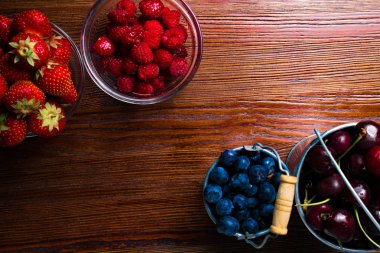 Ahşap arka plan üzerinde meyveleri. Yaz veya bahar organik Berry Wood üzerinde. Çilek, ahududu, yaban mersini ve kiraz. Tarım, bahçecilik, hasat ve diyet kavramı