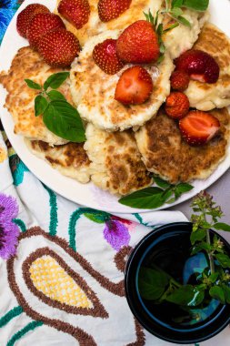 Beyaz bir plaka ile renk çiçek masa örtüsü ile işlemeli nane, melissa dal, Çay üzümlü süzme peynir kek fırından yeni çıkmış. Üstten görünüm
