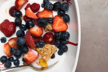 kâse yulaf granola süt, ham ahududu, yaban mersini, çilek ve sağlıklı kahvaltı, en iyi görünüm için Beyaz ahşap tahta kaşık ile fındık